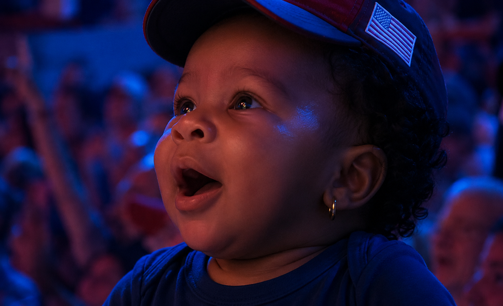 Baby attendee in a patriotic cap watching the celebration lights
